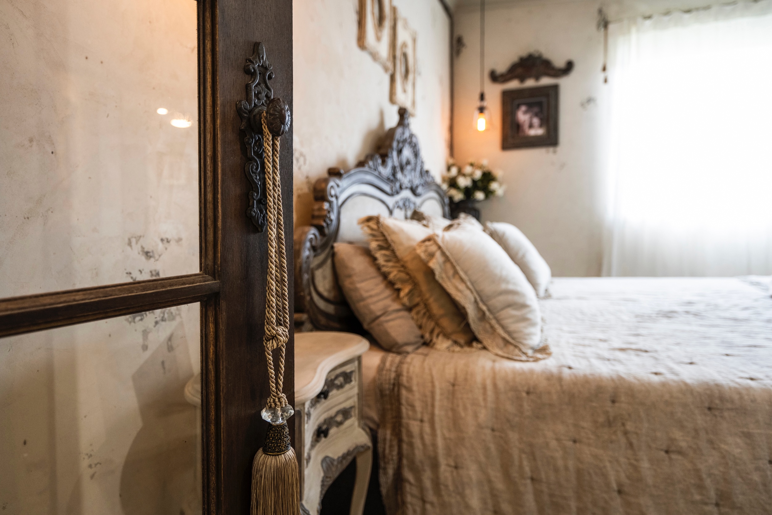 Ornate carved bedframe with layered cushions and warm pendant lighting, Maxwell bedroom styling