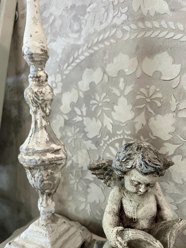 Textured Venetian plaster wall with raised floral pattern, styled with cherub statue