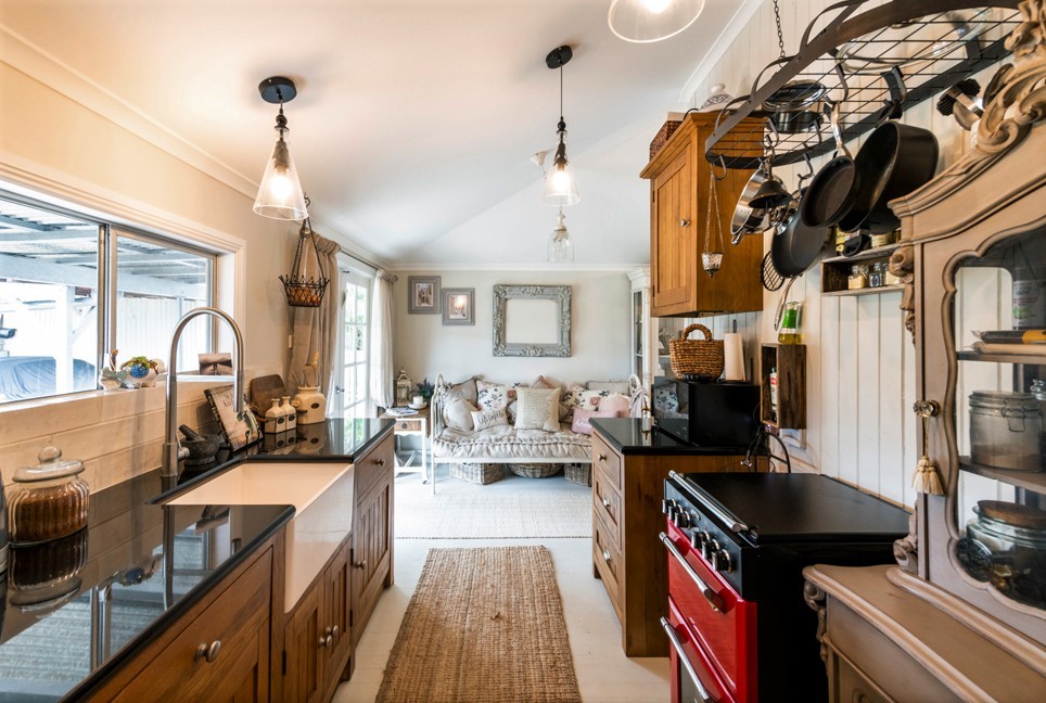 Farmhouse-style kitchen with black granite counters, timber cabinetry and red range, Cambridge kitchen redesign