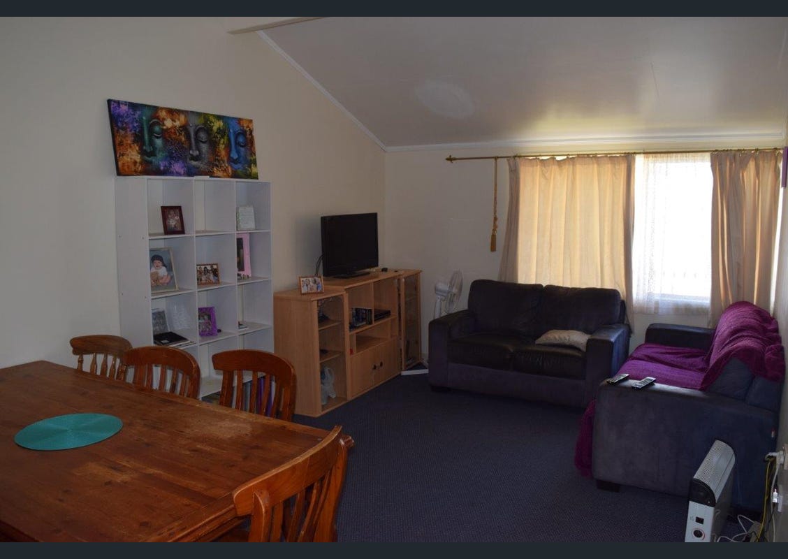 Outdated living room before renovation, dark furniture and cluttered shelving, Cambridge living room redesign