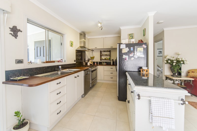 Renovated white kitchen with timber benchtop and dark cabinetry, Jacaranda project after